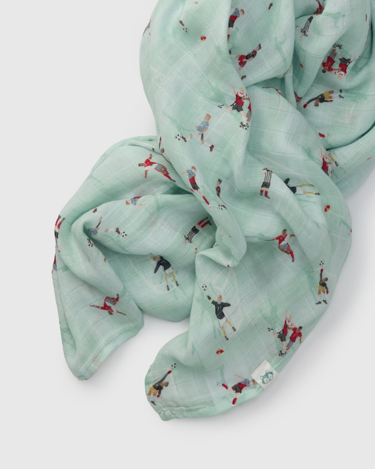 Light blue muslin swaddle with small soccer printed designs on a white background
